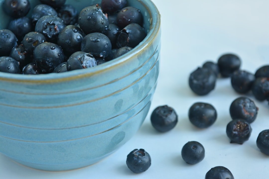 A bowl of thick Greek yogurt topped with a handful of fresh mixed berries like blueberries and raspberries.