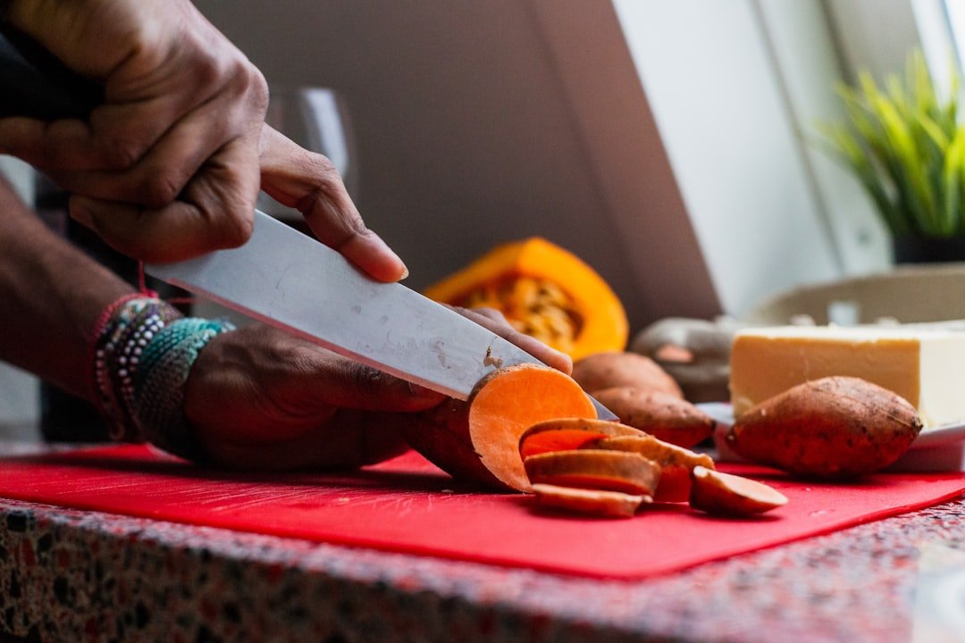 A person smiling while chopping fresh vegetables on a cutting board in a brightly lit kitchen, symbolizing the joy of healthy cooking.